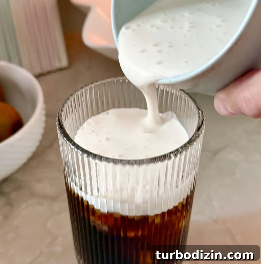 Cold Brew Coffee at Home: Step-by-Step Guide for Smooth Flavor 12 Pouring homemade cold foam creamer over cold brew coffee