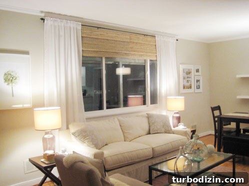 18 Expert Tips for Properly Hanging Curtains and Blinds 2 living room with white sheer curtains hung on oil rubbed bronze curtain rod with bamboo roman shades
