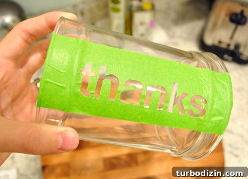 Thanksgiving Thanks Jar Craft: DIY Glass Gratitude Gift 6 Painter tape THANKS stencil stuck to side of glass apothecary jar for Thanksgiving craft