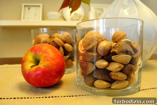 Clear vases filled with mixed nuts and an apple