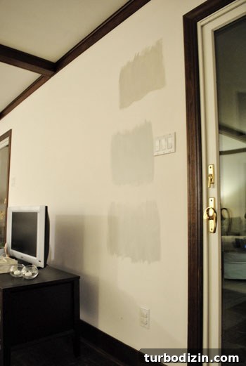 How to Choose the Perfect Gray Paint Color for Your Home 7 three Benjmain Moore gray paint color swatches on a white wall at night time in artificial light