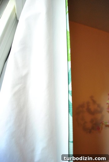 close up of blackout curtain liner fabric placed behind curtain panel in a girl's nursery