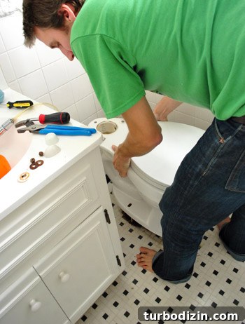 Fix a Wobbly Toilet: Quick Steps to Stabilize It Safely 19 John placing toilet bowl back on floor over new wax ring