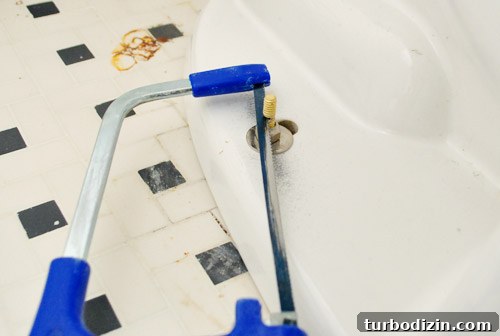 Fix a Wobbly Toilet: Quick Steps to Stabilize It Safely 23 Cutting excess bolt length on toilet bowl with a hacksaw