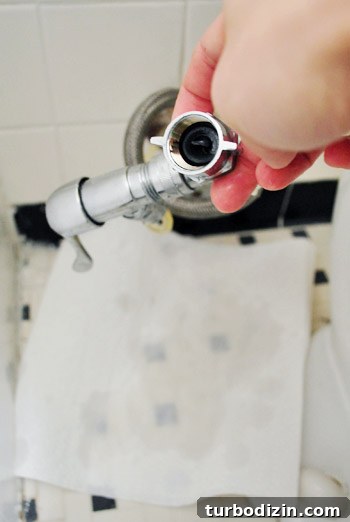 Fix a Wobbly Toilet: Quick Steps to Stabilize It Safely 6 Collecting remaining water in toilet supply line with paper towel on the floor