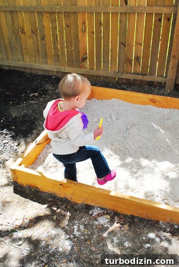 Child playing in newly filled sandbox