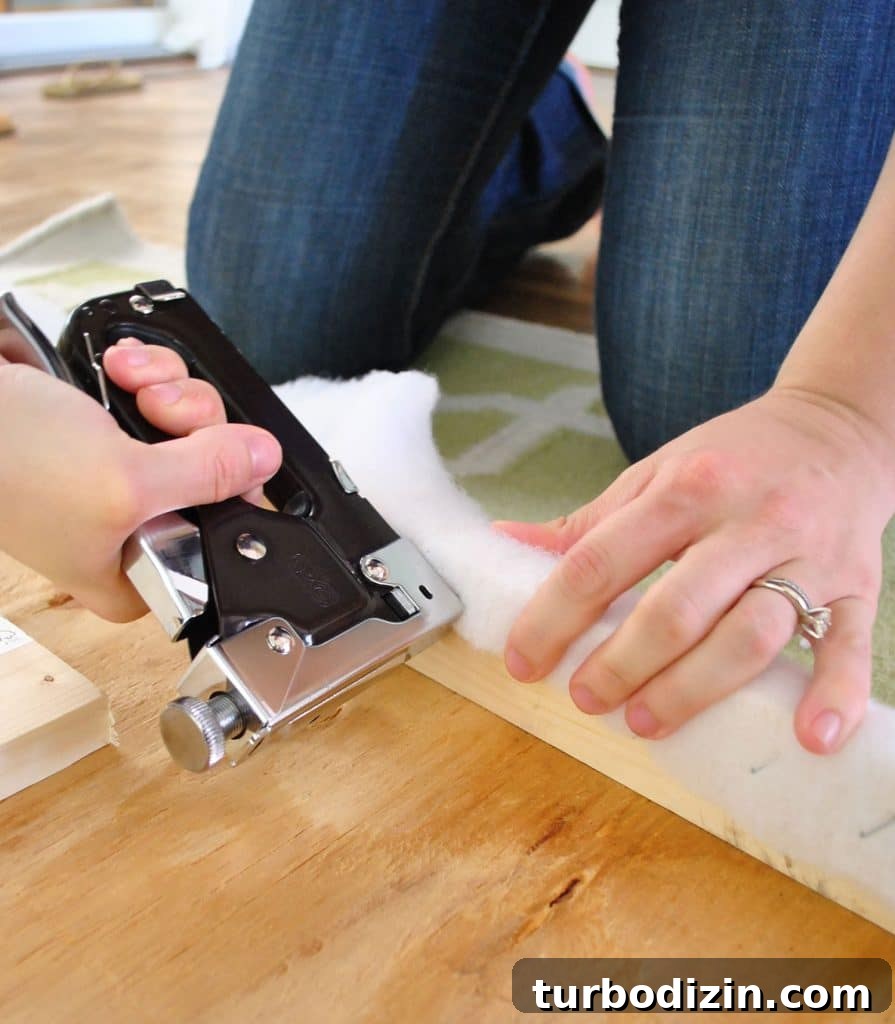 Using staple gun to attach batting to back of DIY upholstered fabric headboard