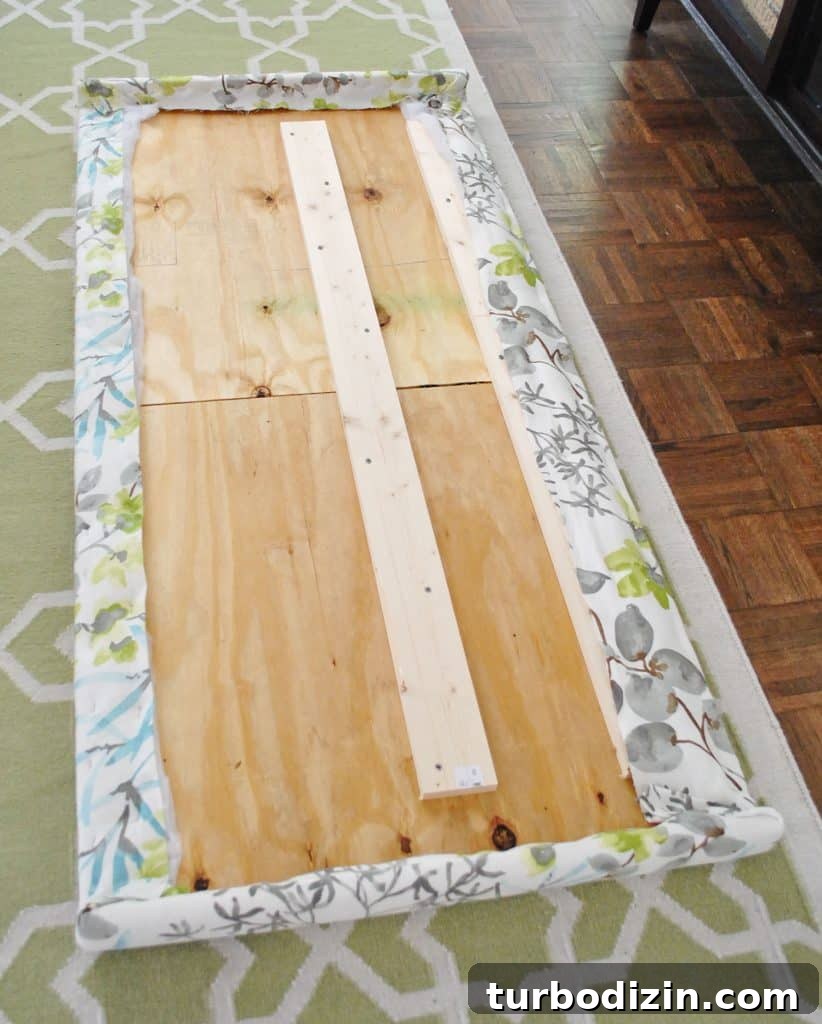 Fabric fully stapled along the backside of wooden headboard frame