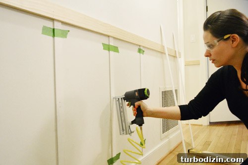 Board and Batten Wall Paneling for Under $60 12 wearing safety goggles and using Craftmans nail gun to install vertical lattice strips to create battens in board and batten DIY project