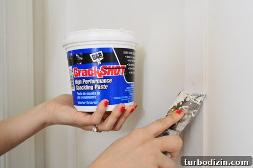 Board and Batten Wall Paneling for Under $60 14 applying DAP CrackShot High Performance Spackling Paste to fill nail holes in wood DIY project