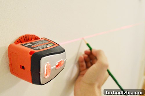 Board and Batten Wall Paneling for Under $60 8 using a black & decker laser level and pencil to mark a level line on a wall