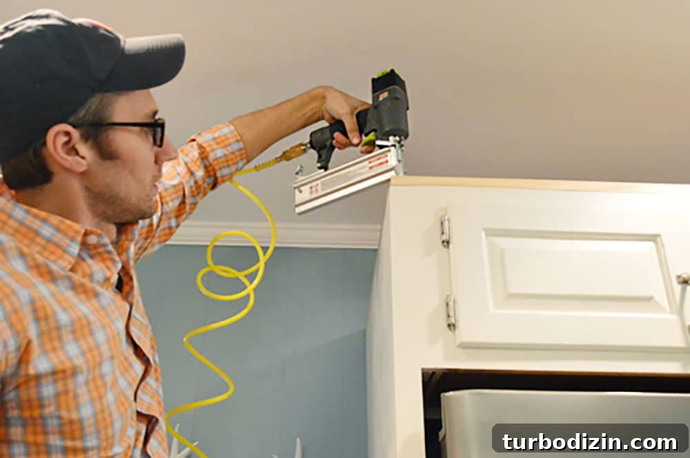 Add Crown Molding to Cabinets: Step-by-Step Guide for a Polished Finish 6 John using nail gun to attached scrap wood to top of cabinet