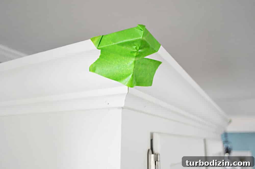 Add Crown Molding to Cabinets: Step-by-Step Guide for a Polished Finish 9 Green painters tape on the corner of kitchen crown molding while glue dries