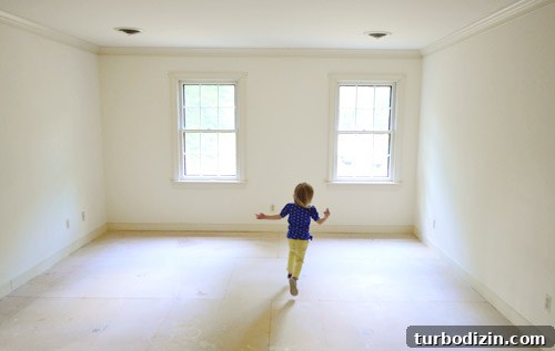 little girl running in empty room with no carpet