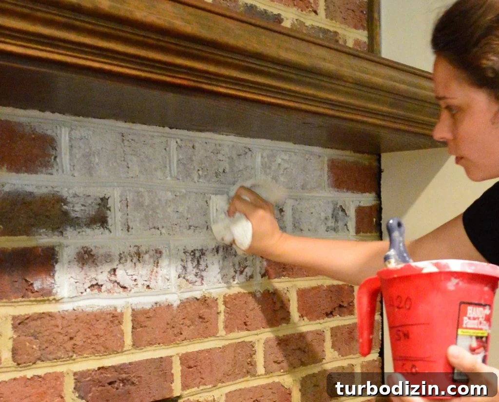 Whitewashing a Brick Fireplace: Step-by-Step Guide for a Fresh Look 6 Sherry dabbing watered down white paint on brick wall