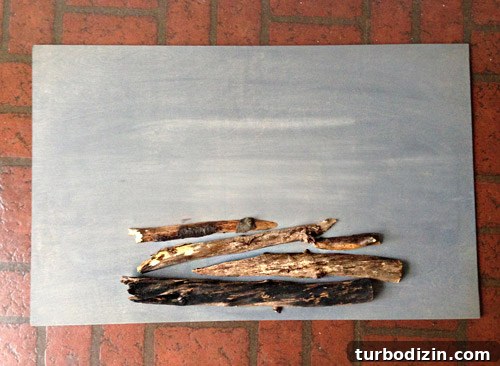 4 DIY Holiday Crafts to Transform Your Home This Season 6 Cut tree branches stacked on gray stained plywood sheet for DIY holiday faux fireplace