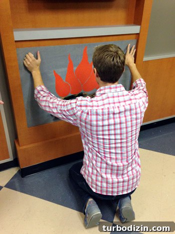 4 DIY Holiday Crafts to Transform Your Home This Season 9 John placing fake fireplace DIY onto mantle in childrens hospital waiting room