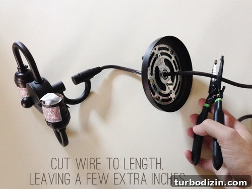 Hand cutting wires on dark pendant light fixture cord