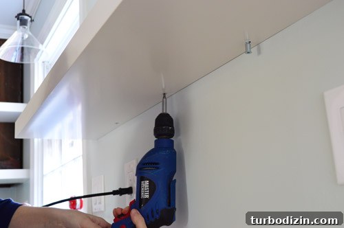 How We Installed Ikea Floating Shelves in Our Kitchen 14 using powerdrill to screw Ikea floating shelf to secure it to wall bracket