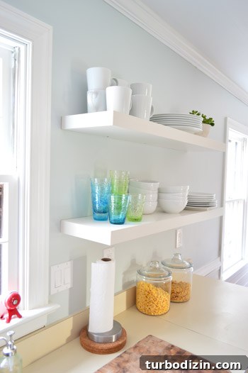 How We Installed Ikea Floating Shelves in Our Kitchen 17 two long Ikea floating shelves in a kitchen holding colorful cups and stacks of white dishware