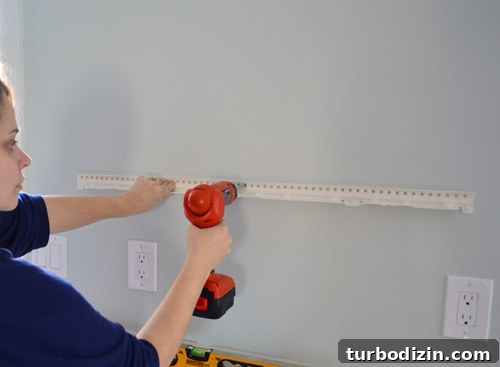 How We Installed Ikea Floating Shelves in Our Kitchen 10 attaching metal hanging bracket for Ikea floating shelf using a drill driver to screw it to kitchen wall