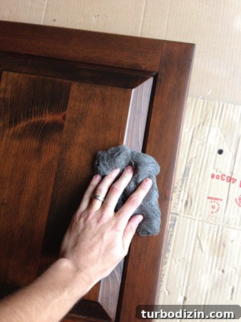 How to Make Wood Cabinets Darker: Step-by-Step Staining Guide 10 Sanding dark stained cabinet door front with extra fine steel wool