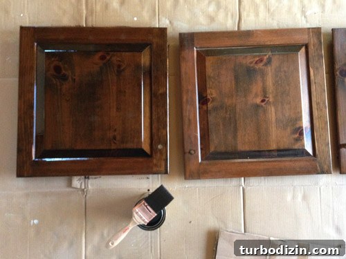 How to Make Wood Cabinets Darker: Step-by-Step Staining Guide 5 Cabinet doors laid flat on cardboard while being stained.