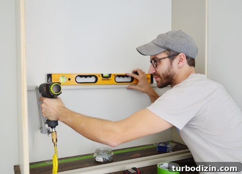 Man using level to nail in shelf support pieces