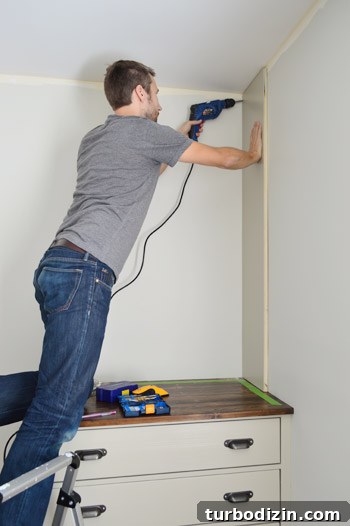 Man attaching side piece of bookshelf attached to a wall