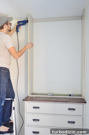 Man screwing into the side of a homemade DIY bookshelf