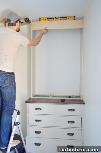 Man adding trim piece at the top of custom bookshelf