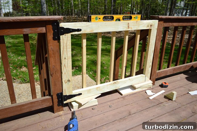 Deck Gate Installed Across Opening In Deck Railing Stairs using Level and Scrap Wood To Hold Into Place