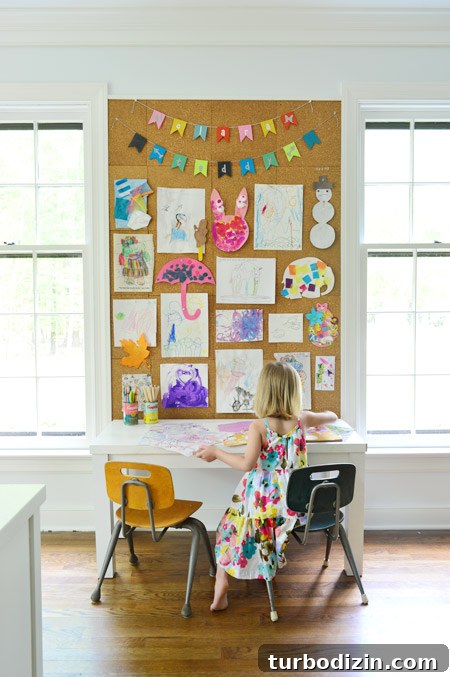 Create a Cork Wall Gallery for Kids’ Artwork 12 kids art displayed on large cork board wall in home office above kids art desk