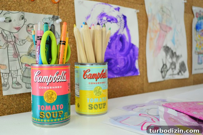 Create a Cork Wall Gallery for Kids’ Artwork 17 limited edition Campbell's soup cans with Warhol labels used to hold supplies pencils and crayons at kid art desk