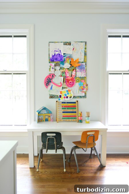 Create a Cork Wall Gallery for Kids’ Artwork 3 small fabric covered cork board used to pin up kid art projects above small homemade desk and schoolhouse style chairs