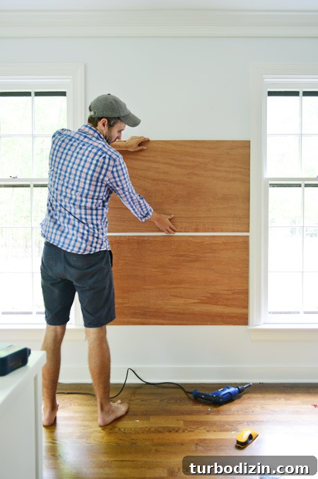 Create a Cork Wall Gallery for Kids’ Artwork 4 dry fitting plywood planks on wall between two windows to become base for gluing cork board tiles to create cork board wall