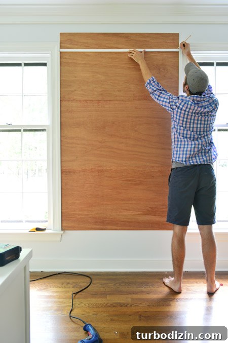 Create a Cork Wall Gallery for Kids’ Artwork 7 marking cut for top plywood piece for cork board wall so that it doesn't extend higher than the window frame