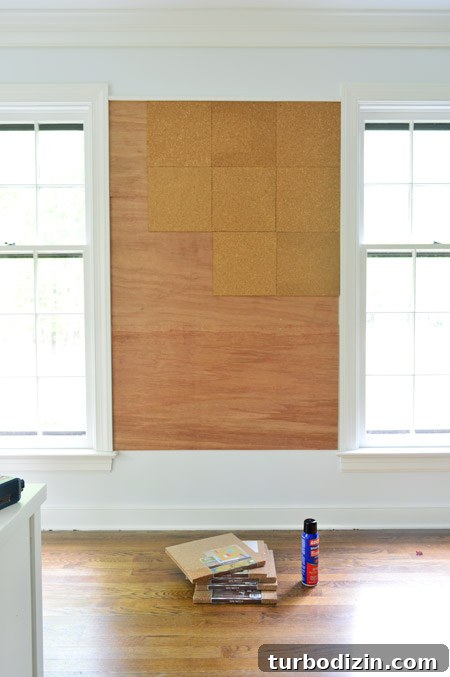 Create a Cork Wall Gallery for Kids’ Artwork 9 applying cork tiles to wall to create oversized cork board wall in kids art area