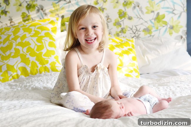 Newborn Photography: A Simple Guide to Shooting Your Baby at Home 12 Big Sister Photo With Newborn Baby Brother In Front Of Colorful Background Fabric