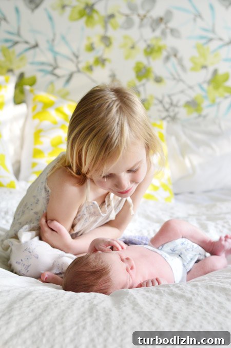 Newborn Photography: A Simple Guide to Shooting Your Baby at Home 13 Big Sister Looking At Infant Baby Brother At DIY Newborn Photo Shoot