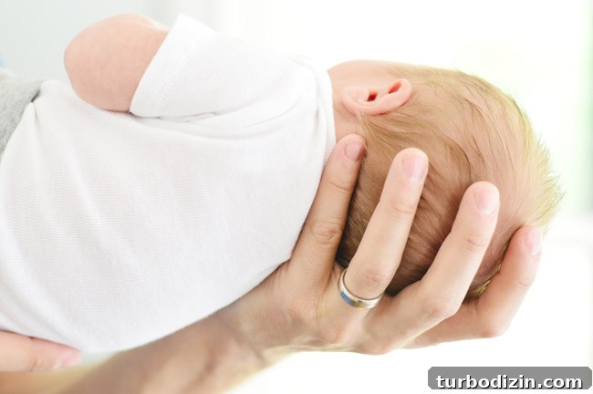 Newborn Photography: A Simple Guide to Shooting Your Baby at Home 10 Dad Hand Holding Newborn Head For Birth Announcement Photoshoot