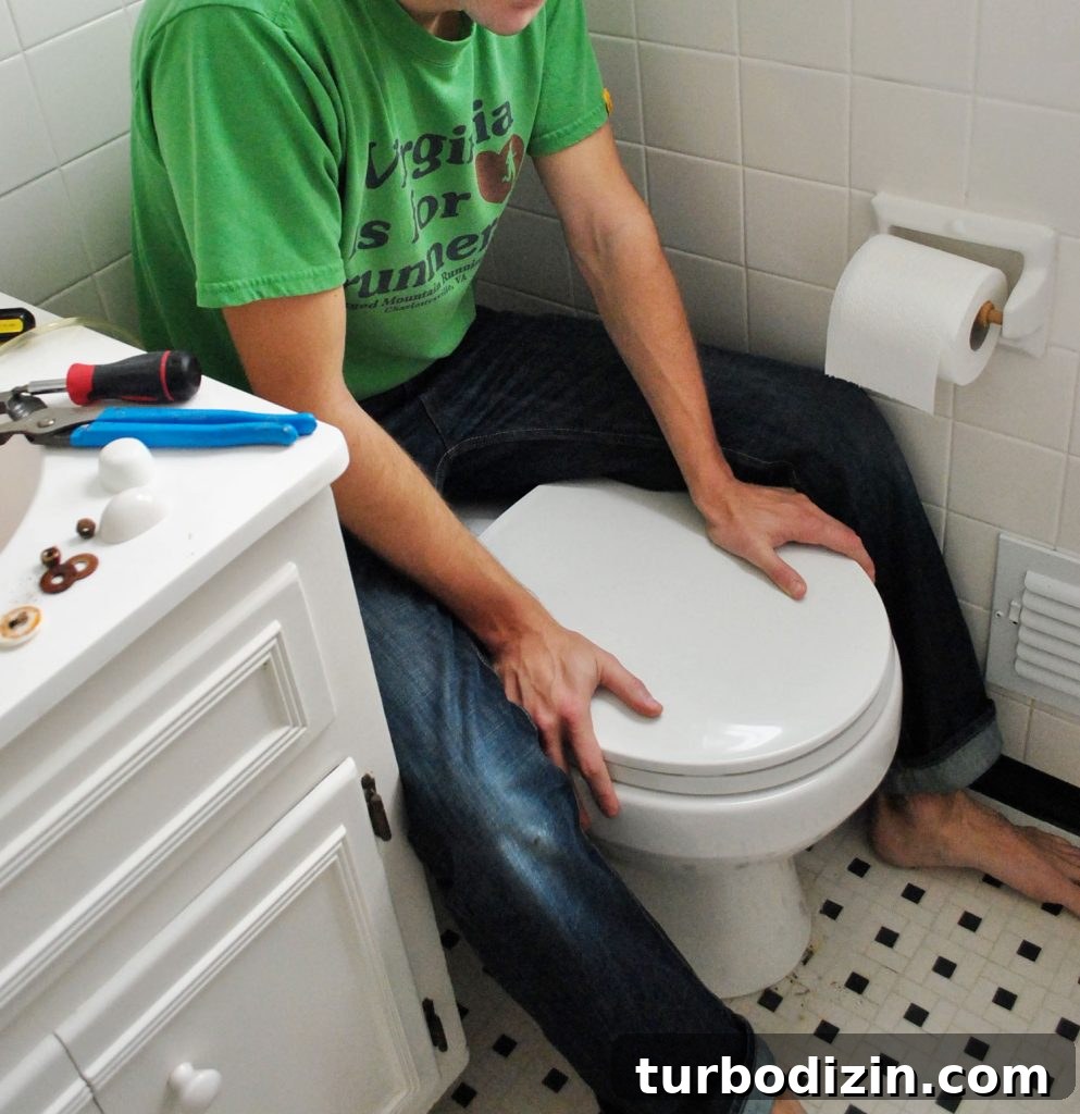 John Sitting On Back of Toilet Bowl To Press Into Place