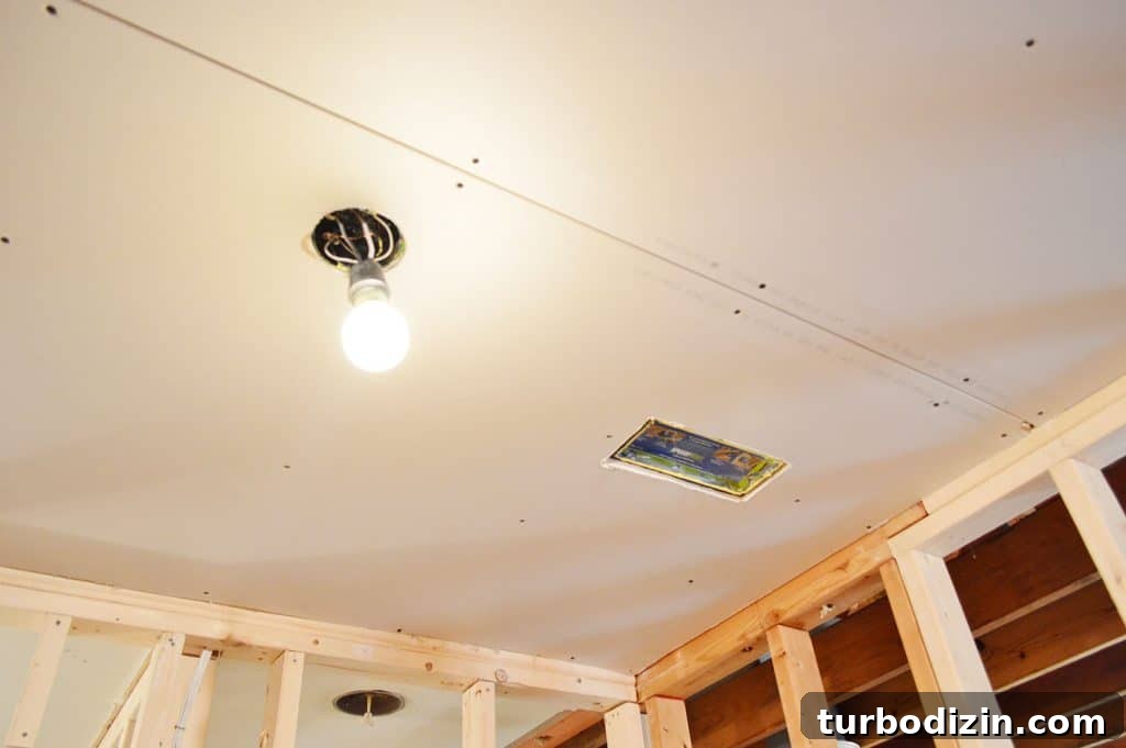 How to Hang Drywall Solo: A Step-by-Step Guide for DIYers 12 drywall hung in ceiling with hole cut for light and HVAC vent