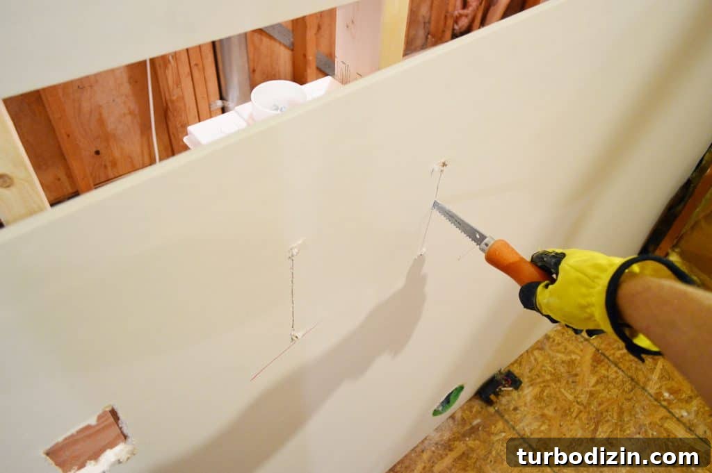 How to Hang Drywall Solo: A Step-by-Step Guide for DIYers 13 using drywall saw to cut hole for laundry plumbing in drywall sheet