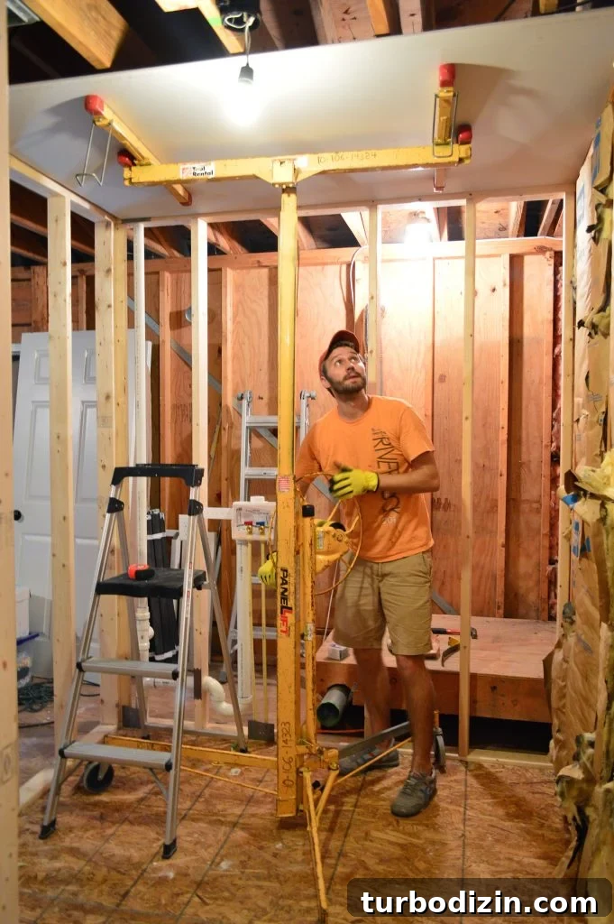 How to Hang Drywall Solo: A Step-by-Step Guide for DIYers 5 John using drywall lift to hold sheet of sheetrock to ceiling