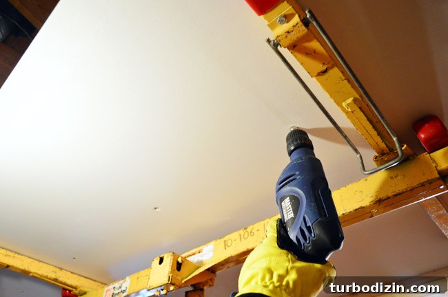 How to Hang Drywall Solo: A Step-by-Step Guide for DIYers 6 attaching drywall sheet to the ceiling using a drill