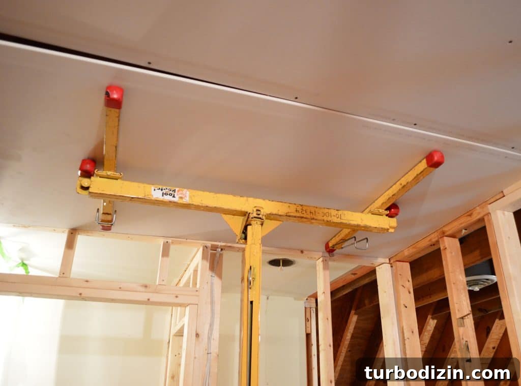How to Hang Drywall Solo: A Step-by-Step Guide for DIYers 10 sheetrock panel held against ceiling of laundry room using drywall lift