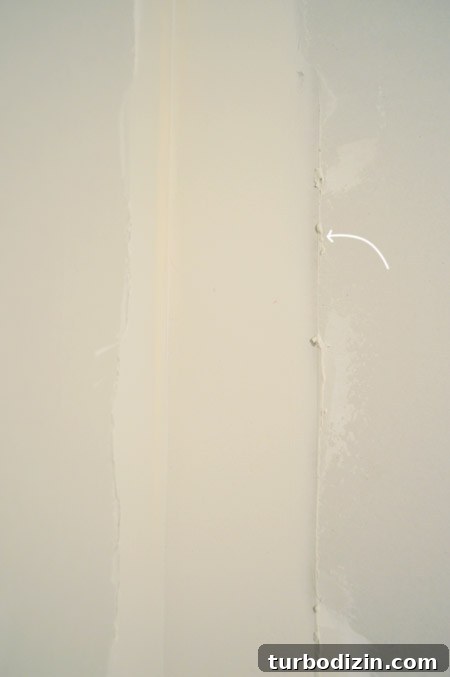 Drywall Taping, Mudding, and Sanding: Step-by-Step Guide 24 arrow pointing to ridge in drywall mud after scraping excess