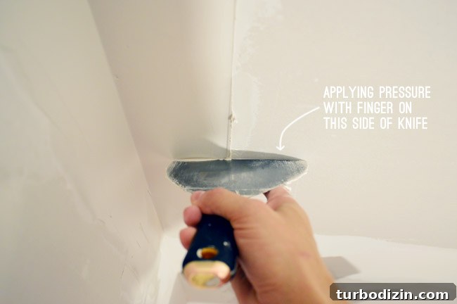 Drywall Taping, Mudding, and Sanding: Step-by-Step Guide 25 flat drywall knife dragging along outer edge of corner with pressure applied to outside of knife
