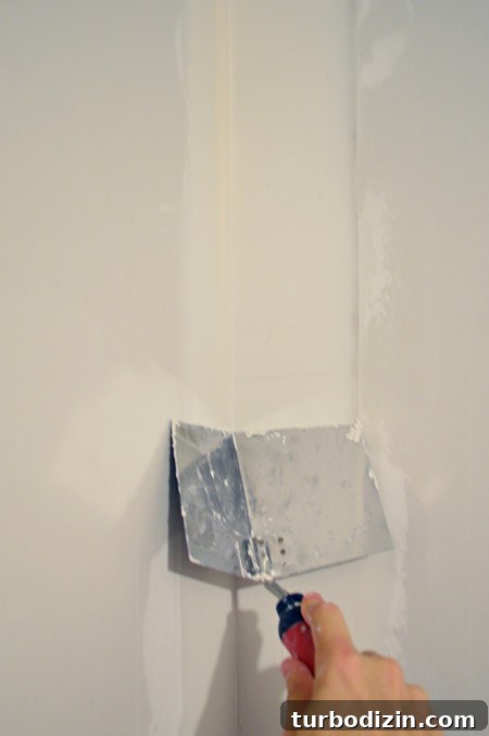 Drywall Taping, Mudding, and Sanding: Step-by-Step Guide 26 dragging corner trowel down corner of drywalled wall